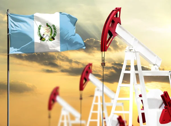 Oil rigs against the backdrop of the colorful sky and a flagpole with the flag of Guatemala. The concept of oil production, minerals, development of new deposits.