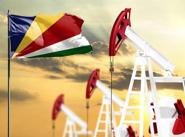 Oil rigs against the backdrop of the colorful sky and a flagpole with the flag of Seychelles. The concept of oil production, minerals, development of new deposits.