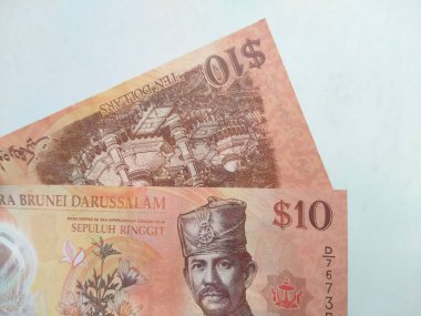 Brunei Darussalam 'ın 10 dolarlık banknotunu beyaz arka planda tutan bir el. 