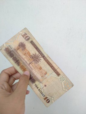 Brunei Darussalam 'ın 10 dolarlık banknotunu beyaz arka planda tutan bir el. 