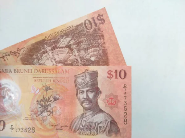 Brunei Darussalam 'ın 10 dolarlık banknotunu beyaz arka planda tutan bir el. 