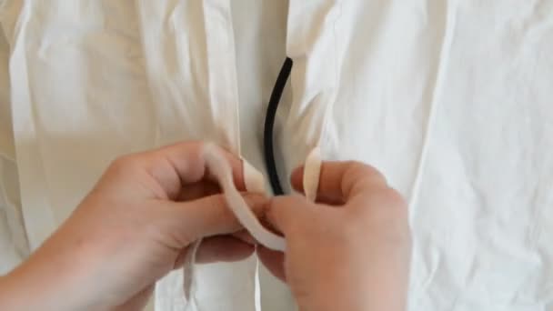 Медсестра помогает доктору подготовиться к операции в больнице, одевая его спереди — стоковое видео