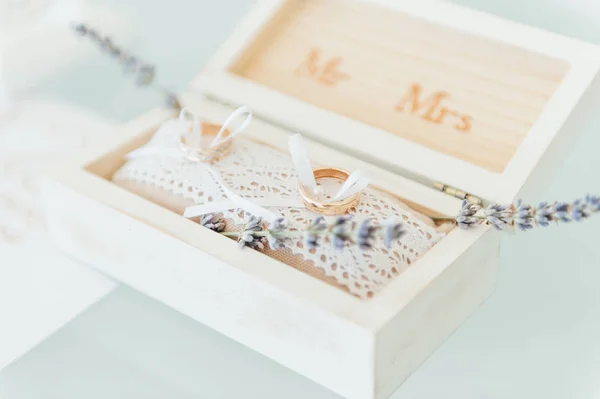 Vista lateral de dos anillos de boda de oro en flores en la vieja caja de madera rústica para la ceremonia de boda . —  Fotos de Stock