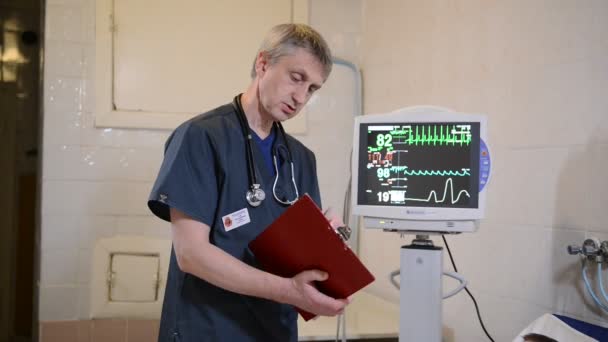 Petit garçon allongé sur le lit d'hôpital et souriant tout en écoutant le médecin masculin écrire sur le presse-papiers — Video