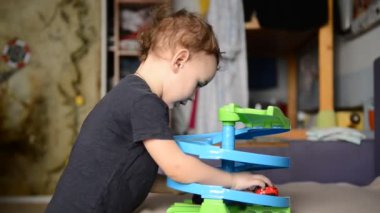 küçük çocuk çocuk odasında oyuncak araba ile oynarken