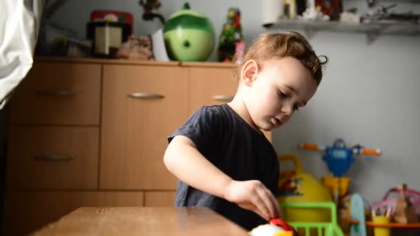 Маленький мальчик играет с игрушечной машиной в детской комнате — стоковое видео
