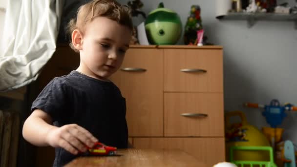 Niño jugando con coche de juguete en la habitación de los niños — Vídeos de Stock