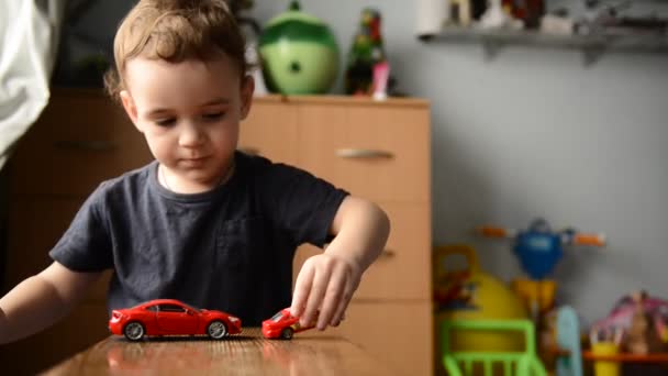 Маленький мальчик играет с игрушечной машиной в детской комнате — стоковое видео