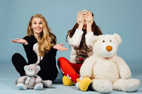 Två lyckliga flickor i pyjamas hålla leksaker i sina händer — Stockfoto