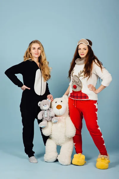 Duas meninas felizes em pijama segurar brinquedos em suas mãos — Fotografia de Stock