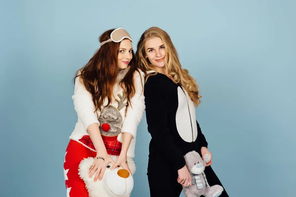 Zwei glückliche Mädchen im Pyjama halten Spielzeug in ihren Händen — Stockfoto