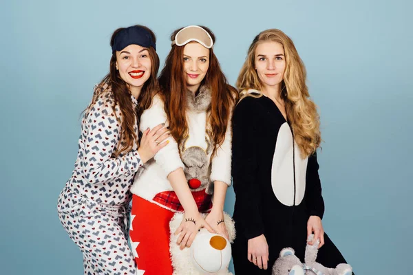 Tre lyckliga flickor i pyjamas hålla leksaker i sina händer — Stockfoto