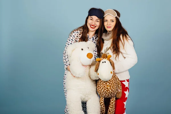 Två lyckliga flickor i pyjamas hålla leksaker i sina händer — Stockfoto