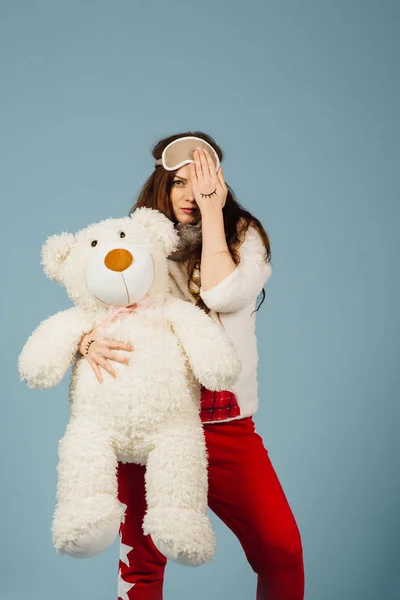 Pelüş oyuncak ayısının sarılma pijama giymiş güzel genç bir kadın — Stok fotoğraf