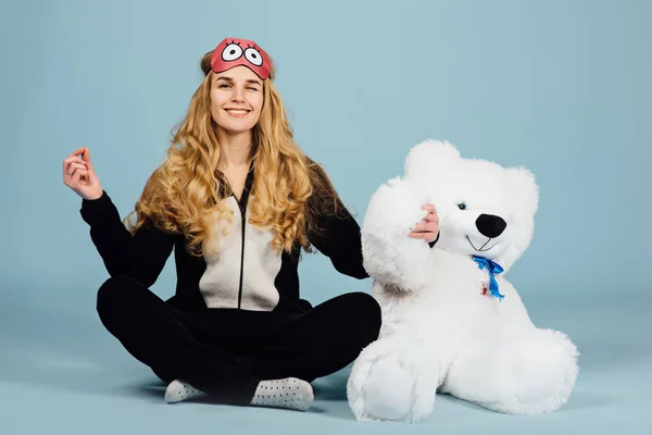 A beautiful young woman wearing pajamas hugging her stuffed teddy bear — Stock Photo, Image