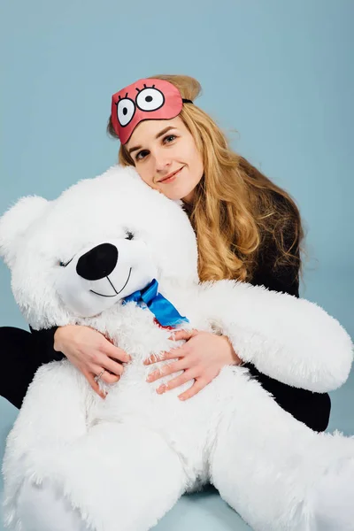 A beautiful young woman wearing pajamas hugging her stuffed teddy bear — Stock Photo, Image