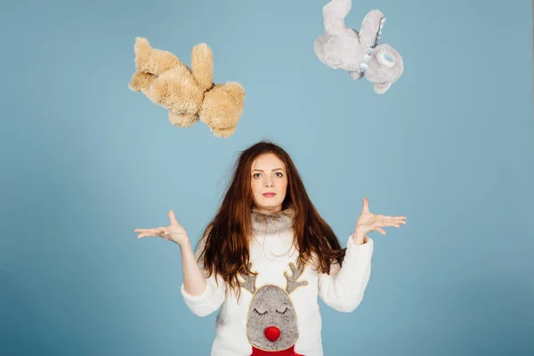 Söt flicka i en tröja med en hjort kastar två leksaker upp — Stockfoto