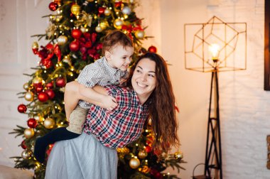 güzel anne xmas ağacının yanındaki kanepede oğlunu kucaklıyor