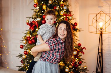 güzel anne xmas ağacının yanındaki kanepede oğlunu kucaklıyor