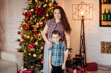 güzel anne xmas ağacının yanındaki kanepede oğlunu kucaklıyor