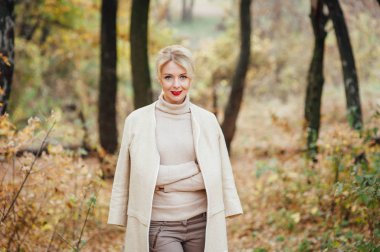 Güzel sarışın kadın sonbahar parkında vakit geçiriyor.