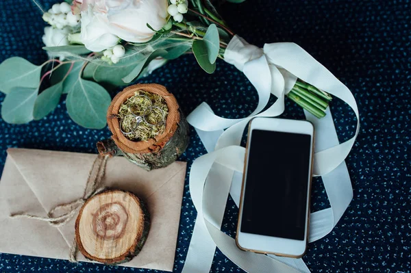 Svatební kytice s kroužky, dřevěná krabička na prsteny, smartphone — Stock fotografie