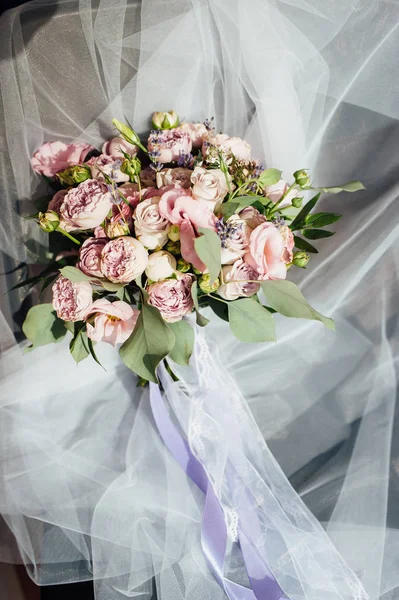 Весільний букет з троянд і півоній лежить на тюлі на стільці — стокове фото