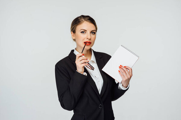 сексуальная деловая женщина в очках и в современном костюме стоит на белом фоне
