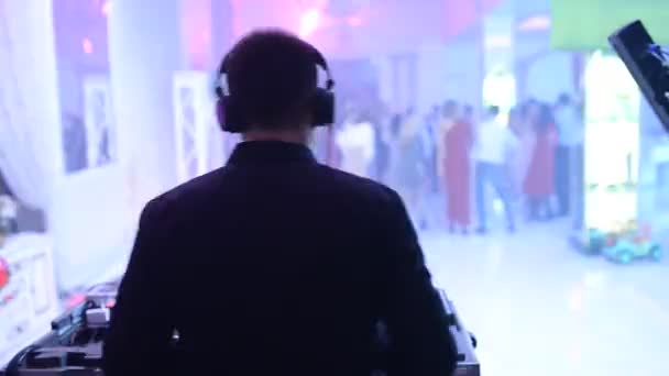 O DJ da discoteca está a trabalhar atrás do telecomando. pista de dança e música leve . — Vídeo de Stock