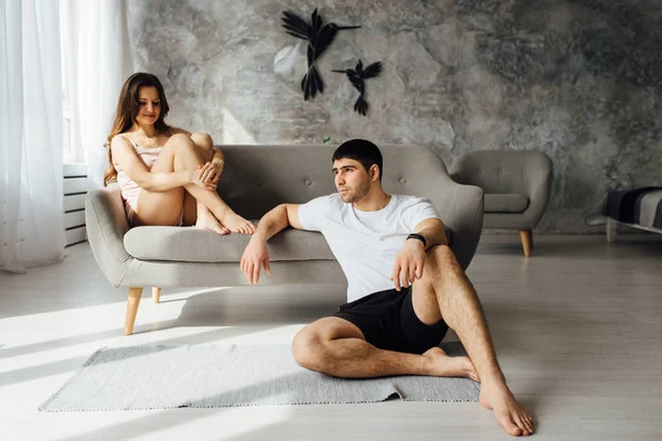 Riendo jóvenes en pijama posando juguetonamente en el sofá. Pareja feliz sonriendo por la mañana — Foto de Stock