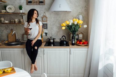 kız beyaz şarap bir bardak ile mutfak masasında oturan