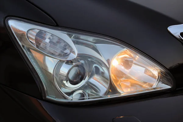 Farol da luz principal do carro preto, close-up . — Fotografia de Stock