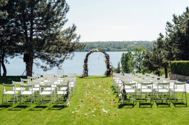 Düğün merasimi için güzel kemer. Konuklar için beyaz sandalyeler.