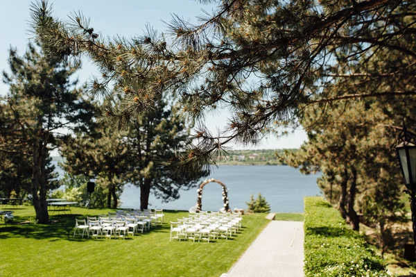 Arco bonito para a cerimônia de casamento no parque com cadeiras brancas para convidados — Fotografia de Stock