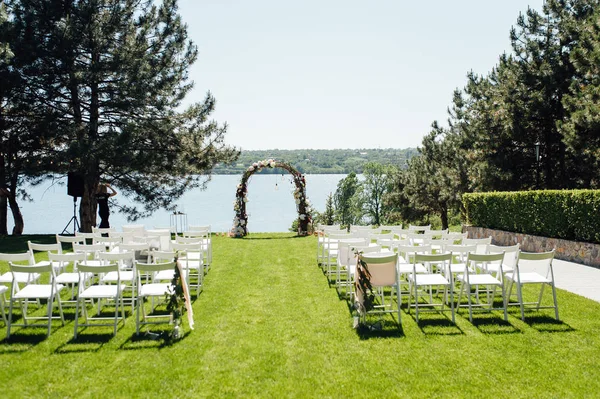 Arco bonito para a cerimônia de casamento no parque com cadeiras brancas para convidados — Fotografia de Stock