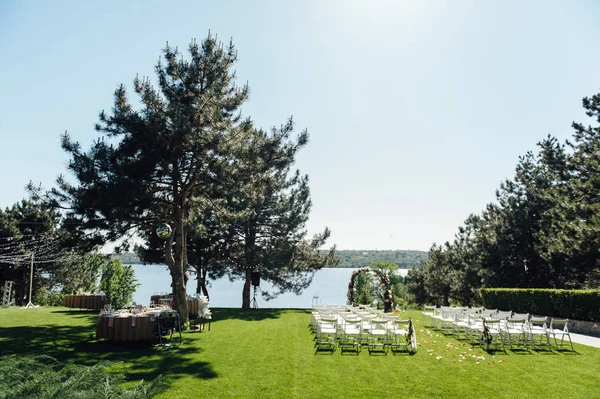 Arco bonito para a cerimônia de casamento no parque com cadeiras brancas para convidados — Fotografia de Stock