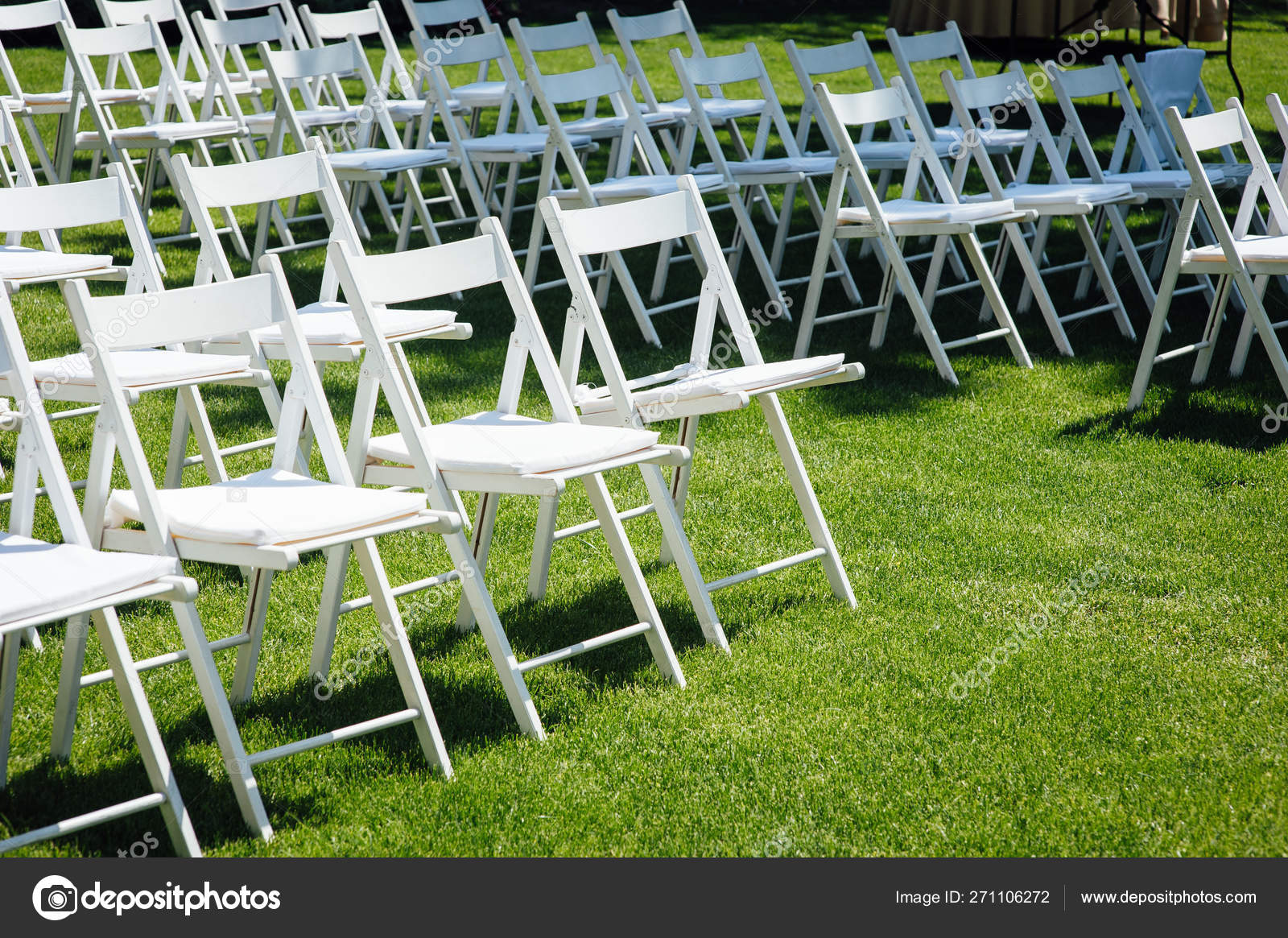 Sebaris kursi lipatan putih di halaman sebelum upacara pernikahan