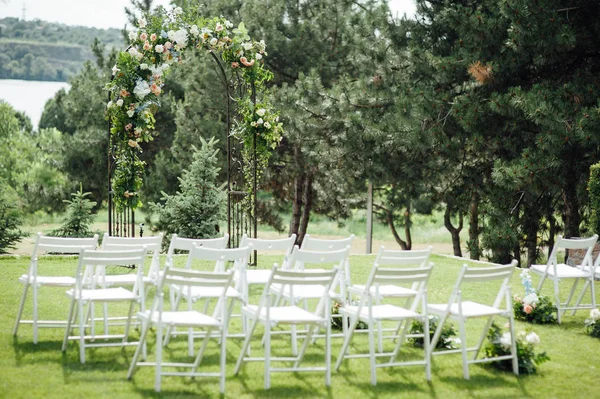 Outgoing wedding ceremony. Decor Studio. white wooden chairs on a green lawn.