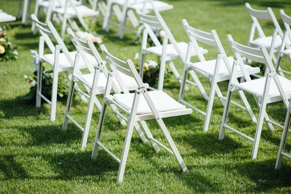 Εξερχόμενη γαμήλια τελετή. Στούντιο ντεκόρ. λευκές ξύλινες καρέκλες σε ένα καταπράσινο γκαζόν. — Φωτογραφία Αρχείου