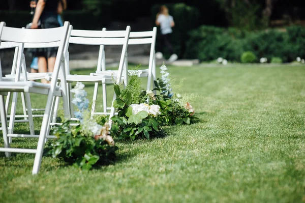 Outgoing wedding ceremony. Decor Studio. white wooden chairs on a green lawn.