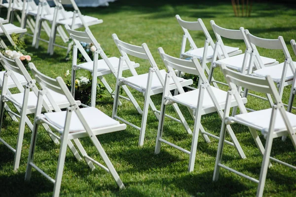 Εξερχόμενη γαμήλια τελετή. Στούντιο ντεκόρ. λευκές ξύλινες καρέκλες σε ένα καταπράσινο γκαζόν. — Φωτογραφία Αρχείου