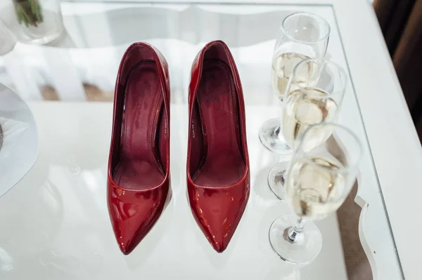 Le scarpe premium da sposa si trovano vicino a bicchieri di champagne. Colore Marsala — Foto Stock