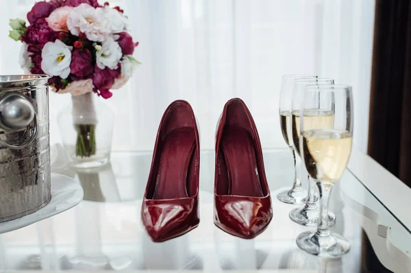 Le scarpe premium da sposa si trovano vicino a bicchieri di champagne. Colore Marsala — Foto Stock