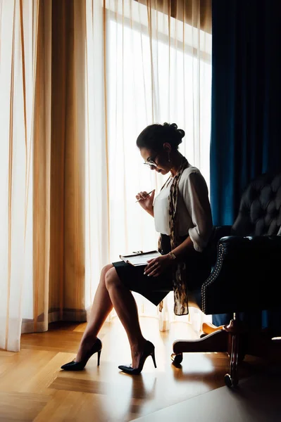 Красивая деловая женщина сидит у окна в кожаном кресле — стоковое фото