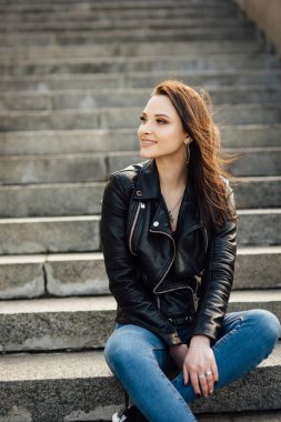 Siyah deri ceketli kız şehirde yürüyor