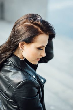 Siyah deri ceketli kız şehirde yürüyor