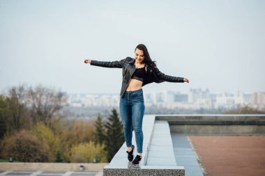 Siyah deri ceketli kız şehirde yürüyor