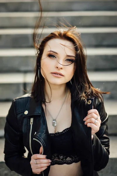 Fille dans une veste en cuir noir marche à travers la ville — Photo