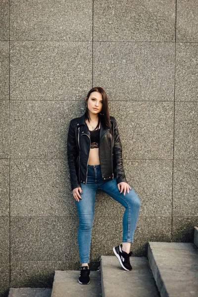 Girl in a black leather jacket walks through the city — Stock Photo, Image