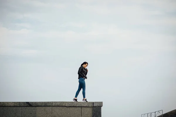 Girl in a black leather jacket walks through the city — Stock Photo, Image